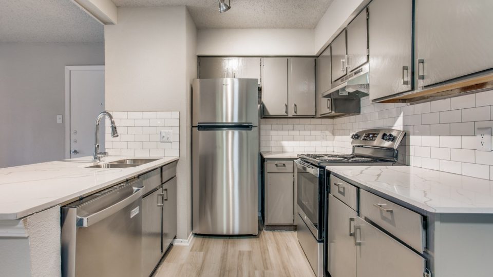 a kitchen with stainless steel appliances and white cabinets at The 8500 Harwood